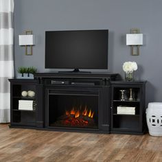 a flat screen tv sitting on top of a black entertainment center next to a fire place