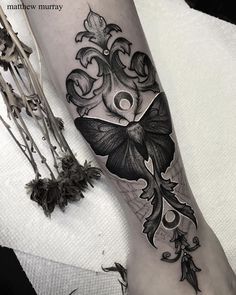 a woman's leg with tattoos on it and flowers in the middle of her arm