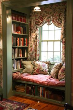 a window seat in the corner of a room with bookshelves and pillows on it