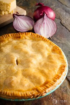 a pie sitting on top of a wooden table next to an onion and cheese dish