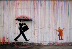 a man holding an umbrella next to a painting of a person with a suit case