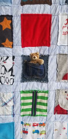 a teddy bear sitting in the pocket of a quilted wall hanging on a wall