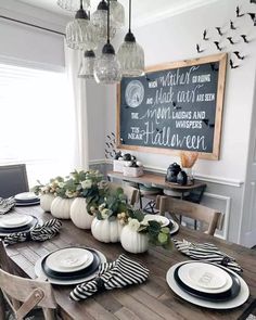 a wooden table topped with white plates and black and white striped napkins next to a chalkboard