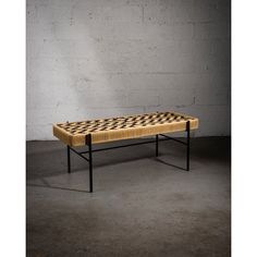 a coffee table with a chess board design on the top and black legs, against a white brick wall