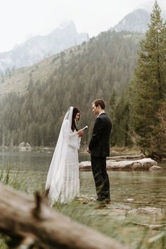 a bride and groom standing in the water at their outdoor wedding ceremony near a mountain lake