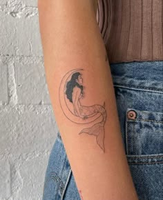 a woman with a mermaid tattoo on her arm