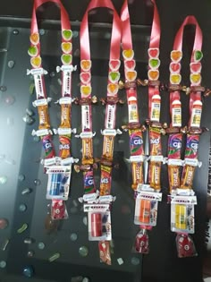 some candy bars are hanging up on a glass shelf with red ribbon around them and gummy candies in the middle