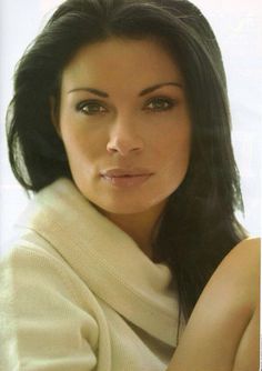 a woman with long black hair is posing for the camera, wearing a white sweater