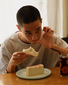 a man sitting at a table with a piece of cake in front of his face