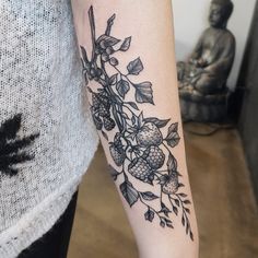 a woman with a tattoo on her arm holding onto a piece of fruit and leaves