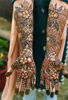 two hands with henna tattoos on them, one is showing the intricate design and the other has flowers