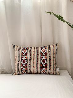 a white bed topped with a pillow next to a window