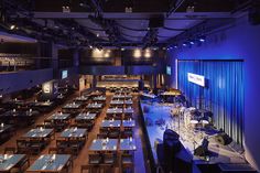 an empty restaurant with blue lighting and wooden tables set up for dinner or other function