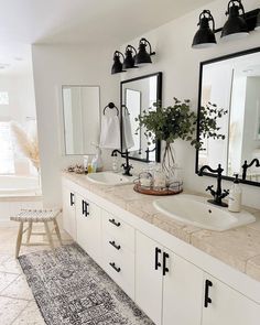 a bathroom with two sinks and mirrors on the wall, along with an area rug