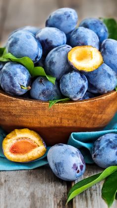 a wooden bowl filled with blueberries on top of a table