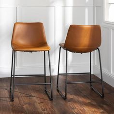 two brown chairs sitting on top of a wooden floor