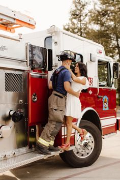 a man and woman kissing in front of a fire truck