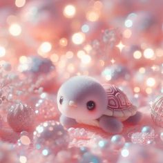 a tiny turtle sitting on top of pink and white glitter covered ground next to christmas ornaments