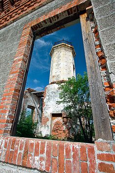 an old brick building with a tower seen through the hole in it's wall