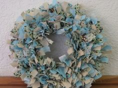 a wreath made out of blue and white paper on top of a wooden table next to a wall