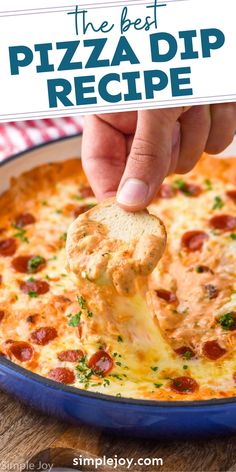 a hand dipping a piece of pizza dip into a blue casserole dish with text overlay