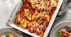 a white casserole dish filled with pasta and sauce on top of a table