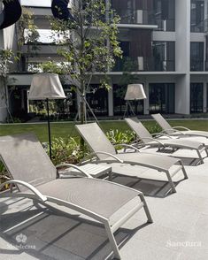 lounge chairs are lined up in front of an apartment building