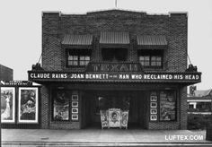 black and white photograph of the front of a building with pictures on it's side