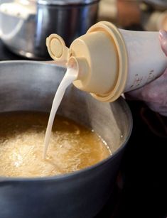 a person pouring milk into a pot filled with food