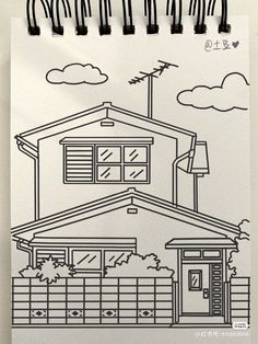 a drawing of a house on a piece of paper with black marker pens in front of it