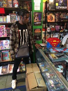 a man standing in front of a display case filled with comics and books at a comic store