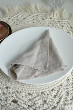 a white plate topped with a piece of cloth on top of a doily covered table