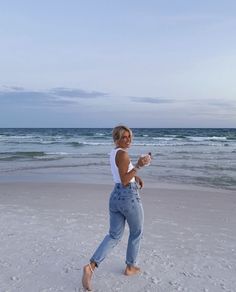 a woman is running on the beach with a frisbee in her hand and smiling