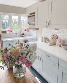 a kitchen filled with lots of counter top space and flowers in vases on the table