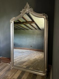 a large silver mirror sitting on top of a wooden floor