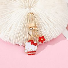 a hello kitty keychain hanging from a tassel on a white fan shaped object