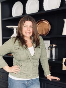 a woman standing in front of a black bookcase with white plates on top of it