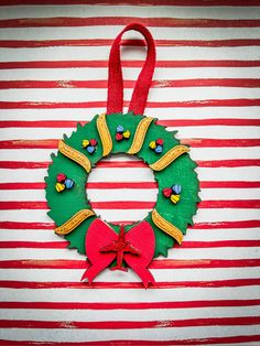 a christmas wreath made out of felt on top of a striped wall with red and white stripes