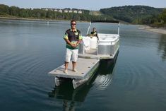 a man standing on the end of a boat in water with another person behind him