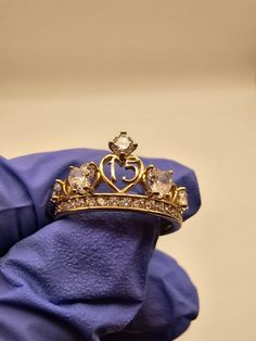 a gold ring with diamonds and a crown on it's side sitting on a purple cloth