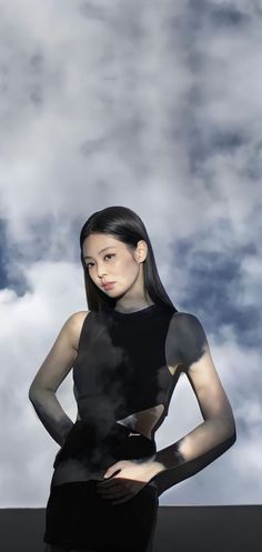 a woman standing in front of clouds with her hands on her hips