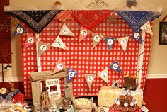 a table topped with lots of cakes and desserts next to a red checkered wall