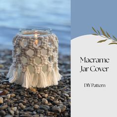 a crocheted jar cover sitting on top of rocks next to a candle holder