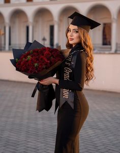 a woman wearing a graduation gown and holding a bouquet of flowers in front of a building