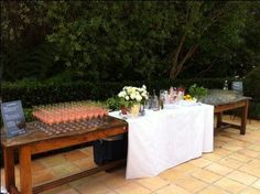 the table is set up with wine glasses and flowers on it for an outdoor party