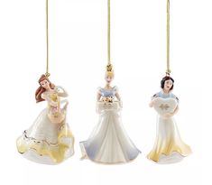 three christmas ornaments are hanging from chains on a white background, one is wearing a dress and the other has a tiara