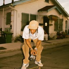 a man riding a skateboard down the side of a road next to a house