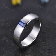 a white gold wedding ring with a blue stone in the center