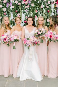 the bride and her bridesmaids pose for a photo in front of a floral wall