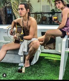 two men sitting on top of a bench with drinks